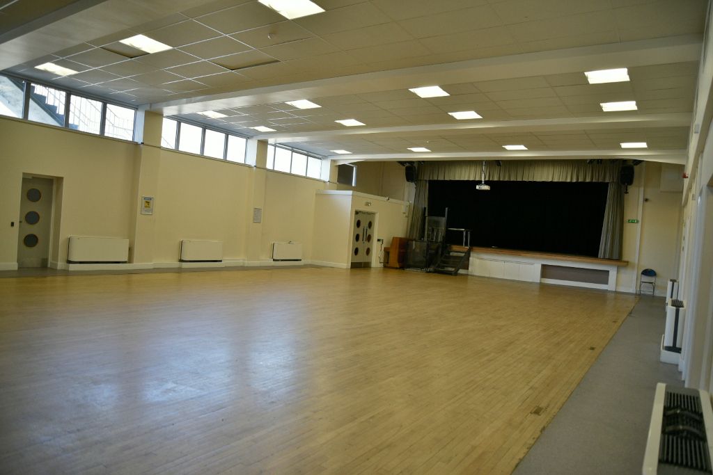 The Ripple Centre main hall with a stage at one end and high windows along the side.