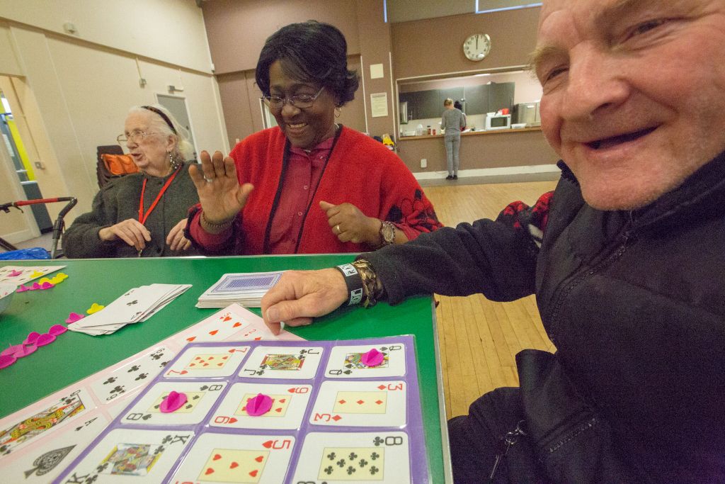 Community group playing a game with large playing cards in the Ripple Centre hall.